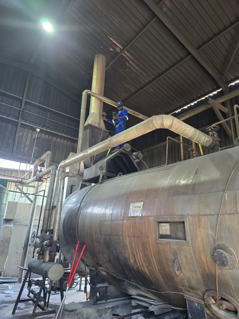 SunWise technician working above a large industrial boiler and its exhaust ducting during emission monitoring