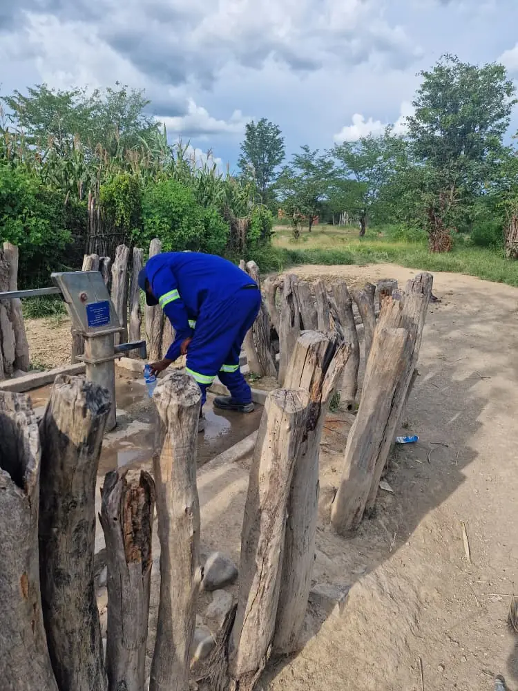 A SunWise technician collecting a groundwater sample from a community borehole hand pump