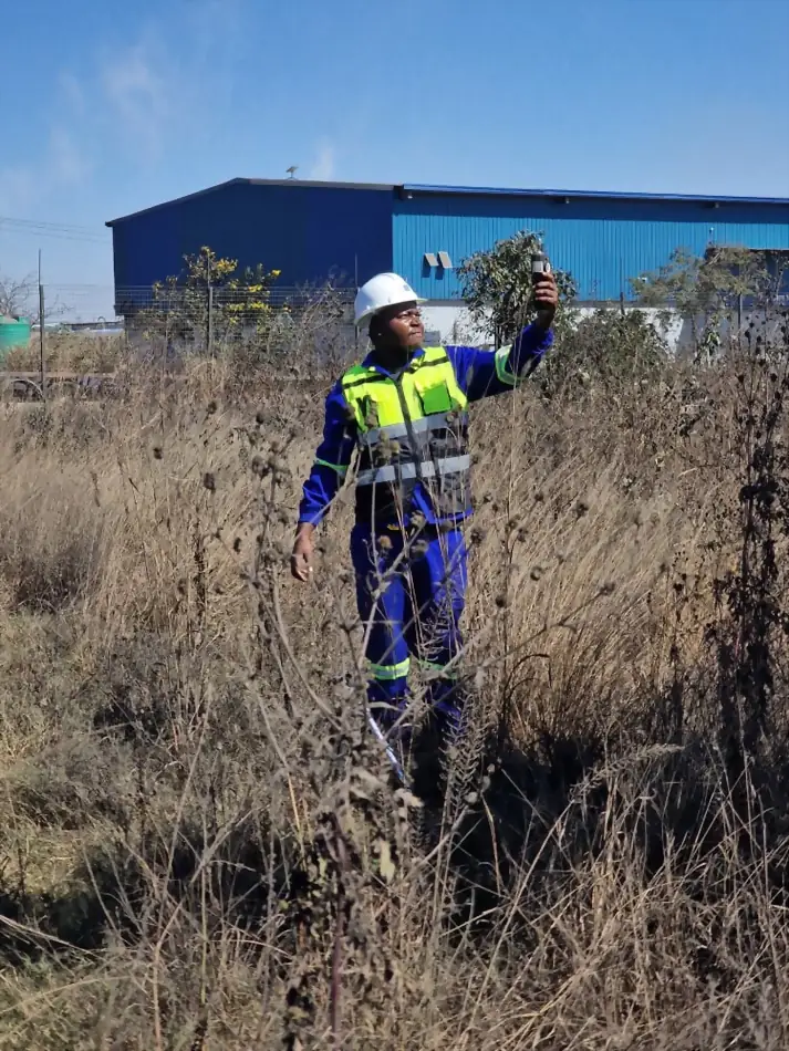 SunWise technician taking a handheld air quality reading at the boundary of an industrial facility