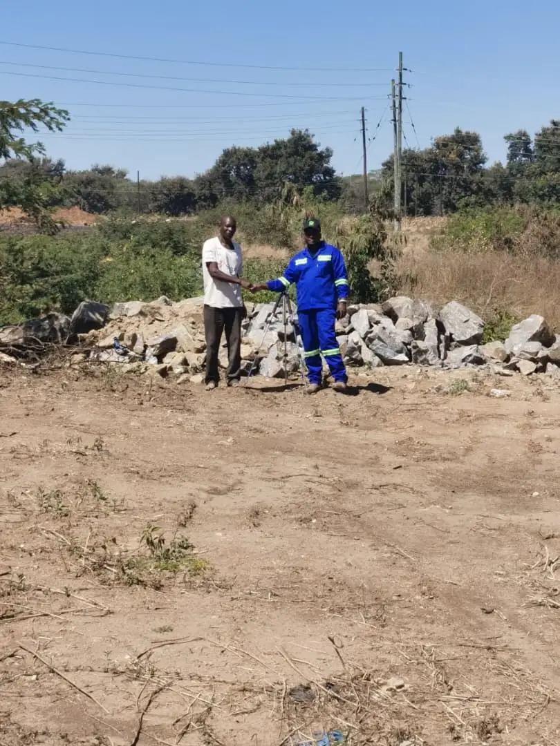 SunWise team member and a site representative standing among excavated rock and bare ground