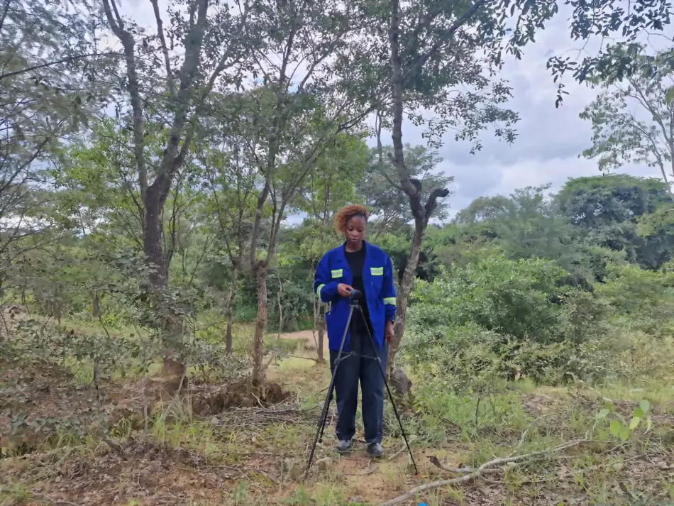 Tripod-mounted noise monitoring instrument set up among trees for an environmental noise survey