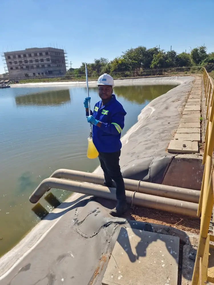 SunWise technician collecting a water sample at a client reservoir for environmental monitoring
