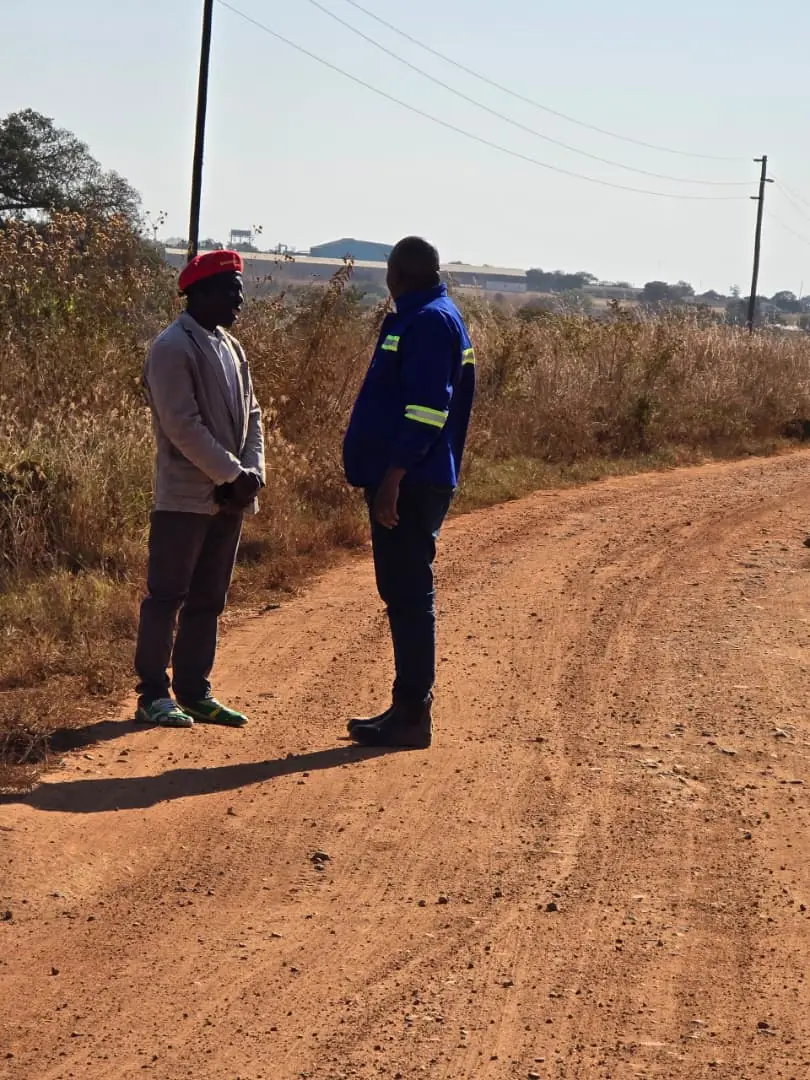 A SunWise team member in company workwear speaking with a resident during a site visit in rural Zambia