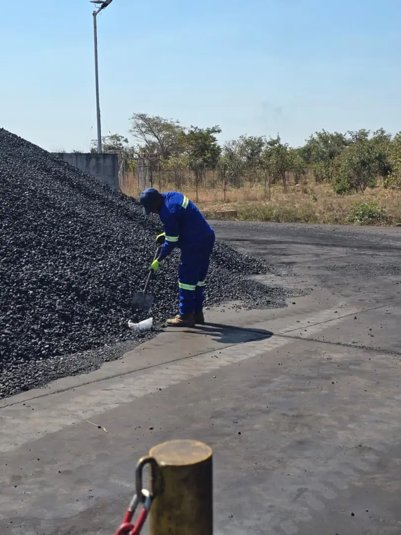 SunWise technician crouching at the base of a bulk stockpile, collecting material into a sample container