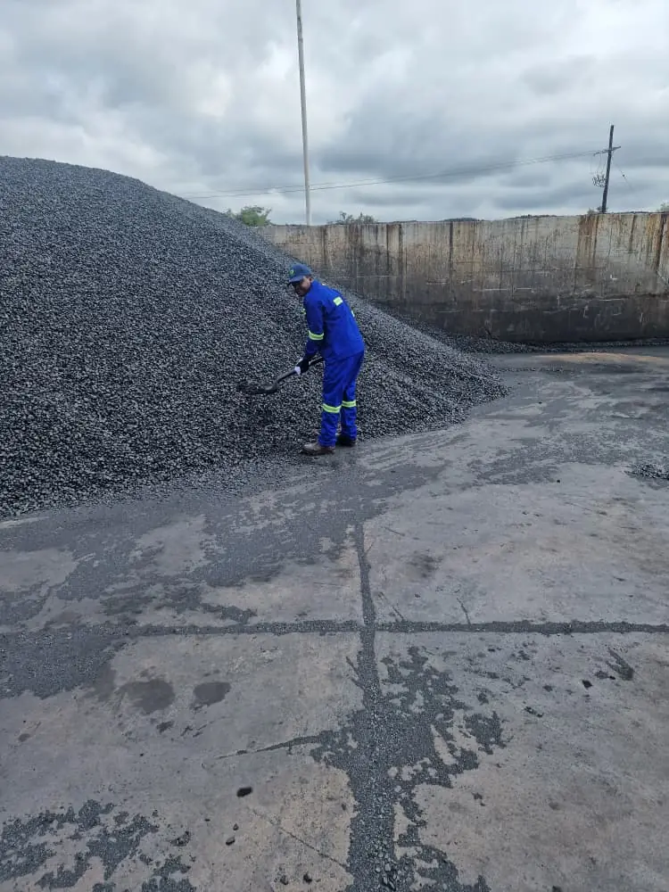 SunWise technician taking a sample from a large bulk material stockpile in an industrial yard