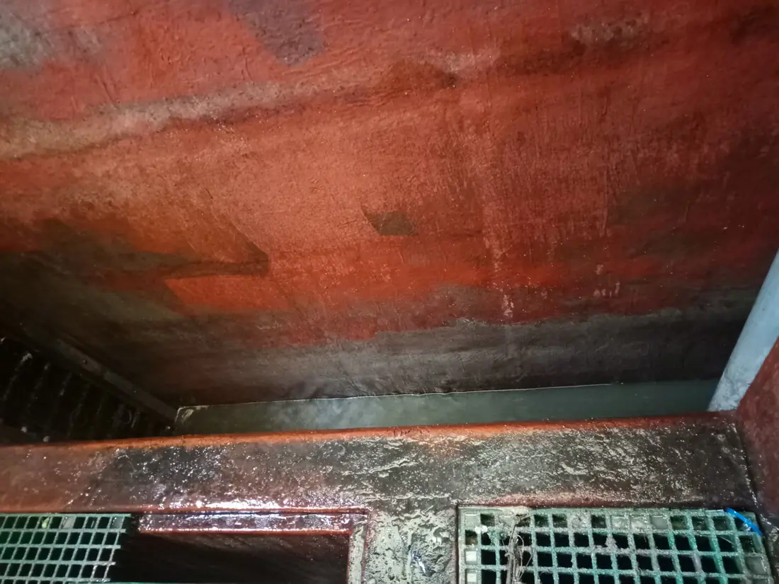 Cleaned interior of a steel storage tank with bare internal walls, pipework and floor grating