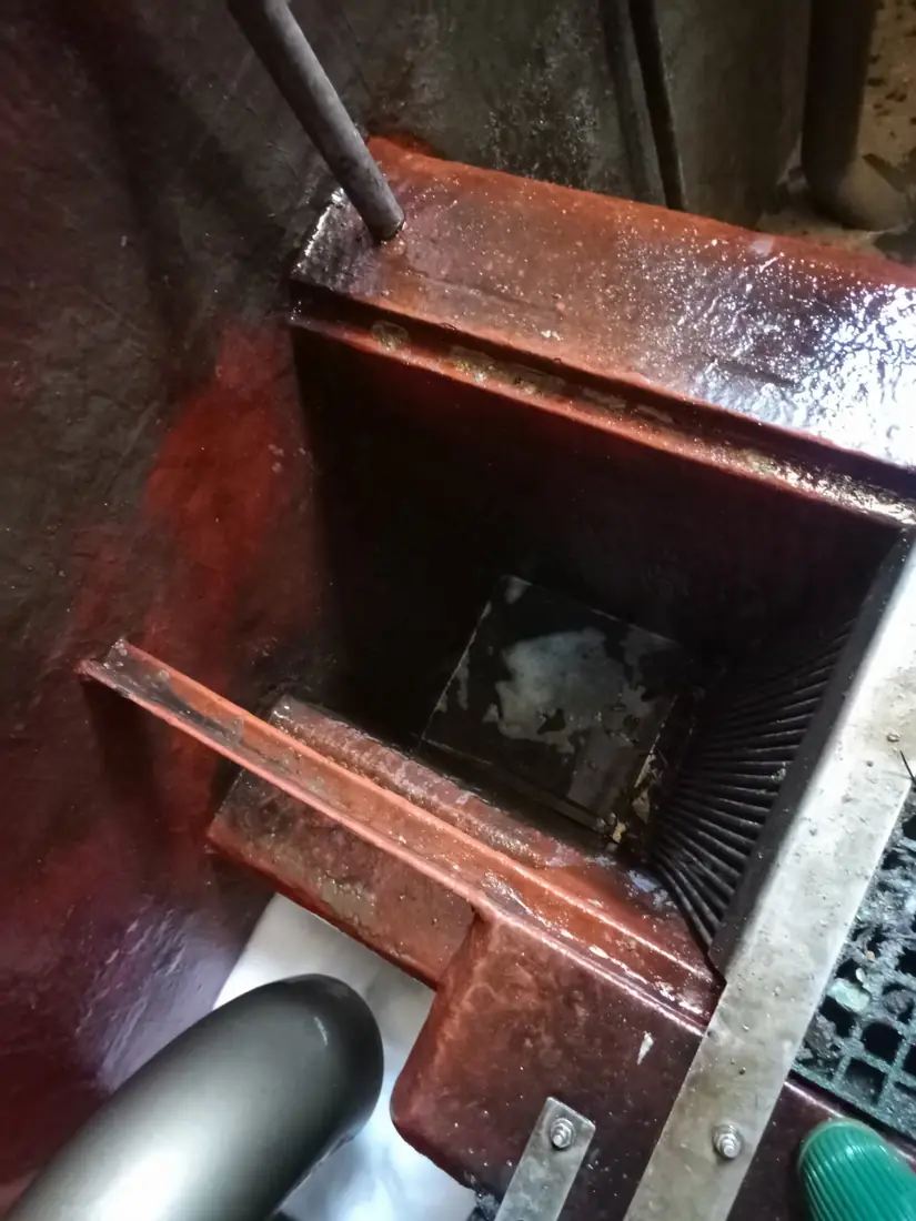 Access grating and steelwork inside a cleaned storage tank, with pipework running through the chamber