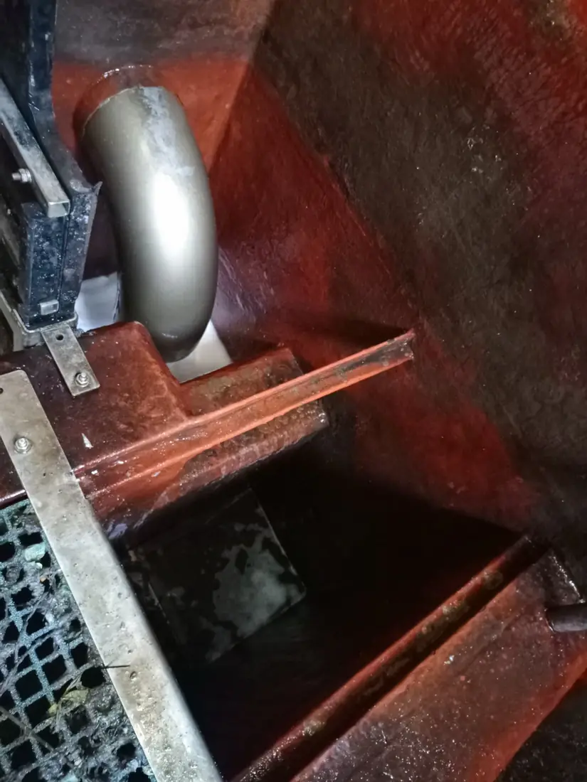 Outlet chamber of a cleaned steel tank showing pipework, steel kerb and reinstated floor grating