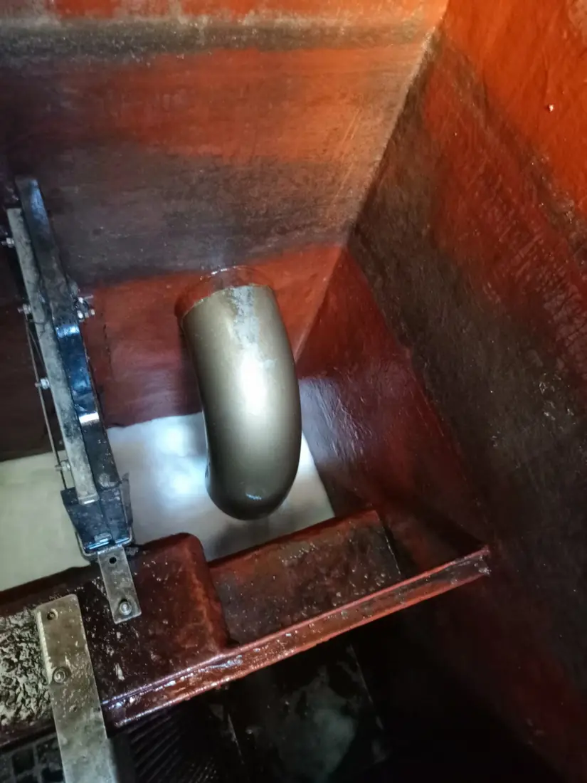 Internal steel partition and bolted fixings inside a cleaned storage chamber, with a stainless pipe elbow behind
