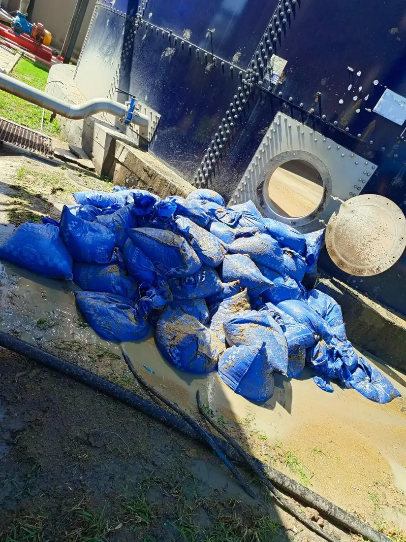 Bagged sludge and residue removed from a storage tank, stacked beside the open tank hatch